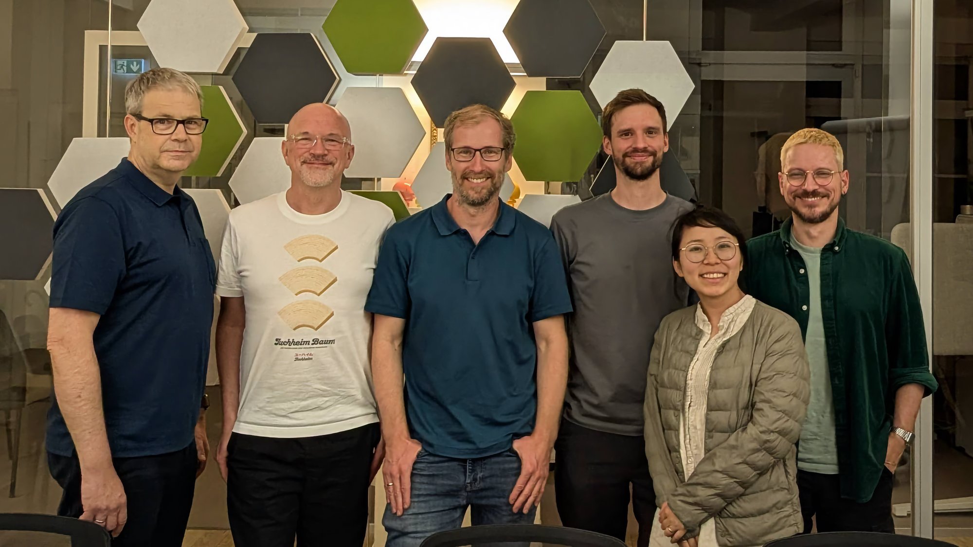 A group of five white men and one Asian-looking woman are posing for a group photo.